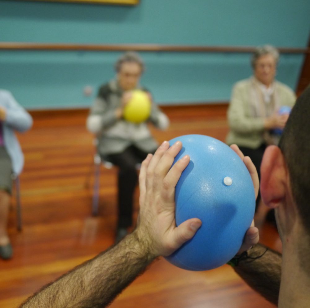 Sesión de ejercicio grupal con pelotas para personas mayores con enfermedades neurológicas