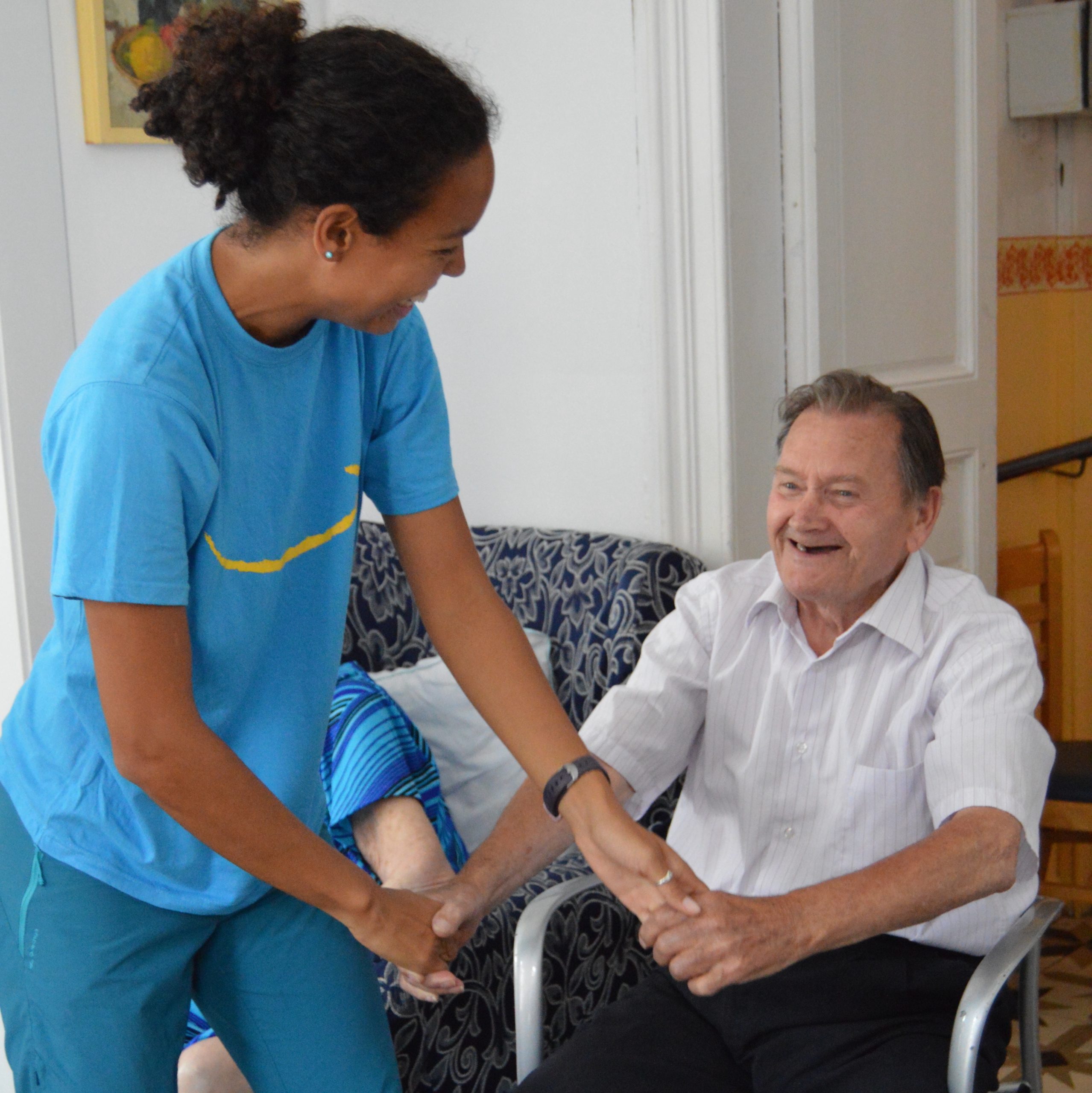 Entrenadora ayudando a un hombre mayor en silla a realizar ejercicios físicos adaptados